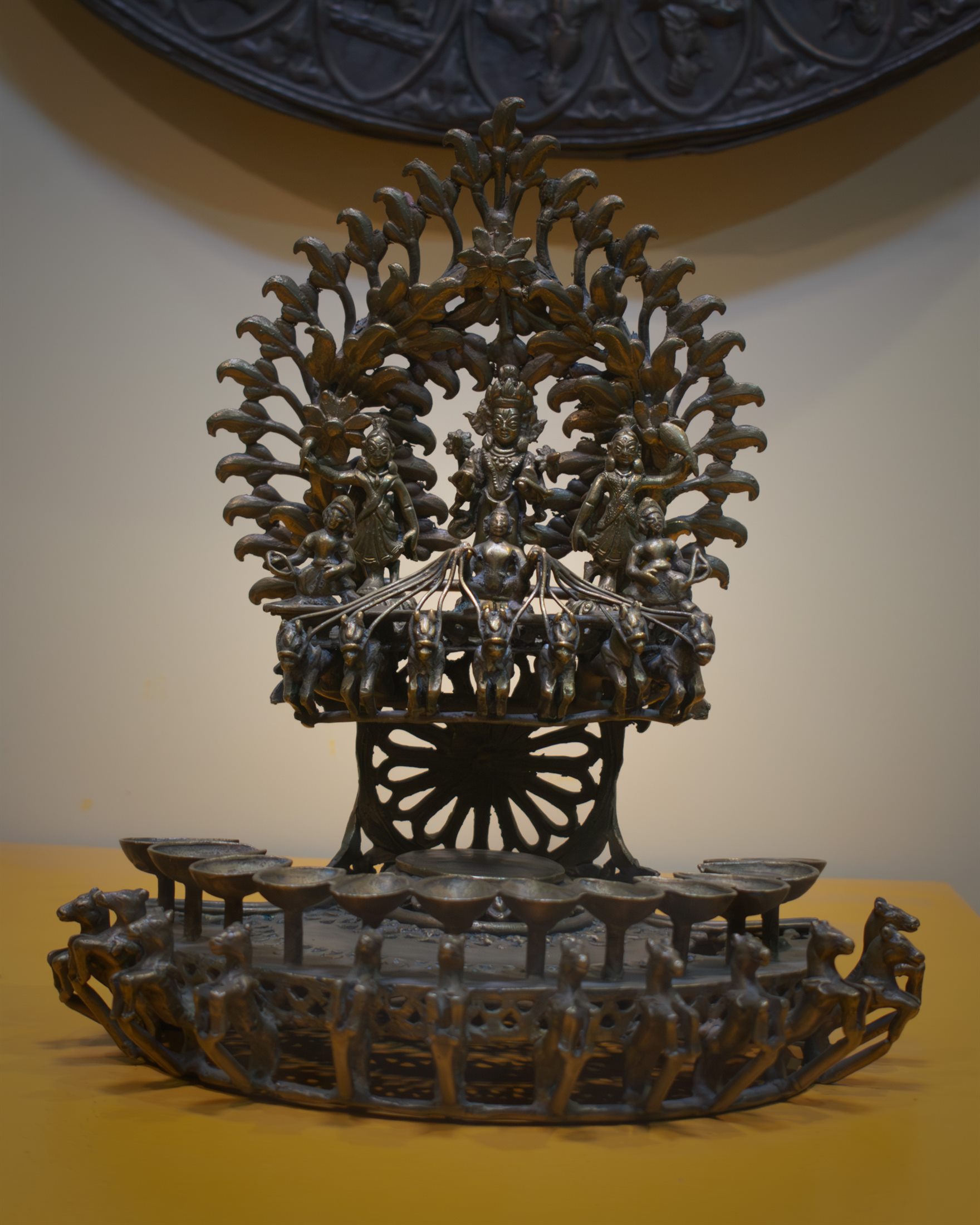 A bronze Surya deep displayed against a warm wall
